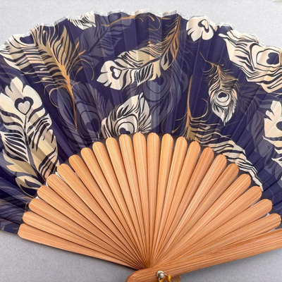 Handheld fan with peacock feather pattern on a gray background
