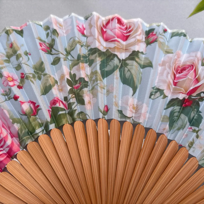 Floral-patterned hand fan with pink roses on a gray background