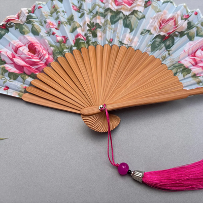 Floral-patterned hand fan with pink roses on a gray background