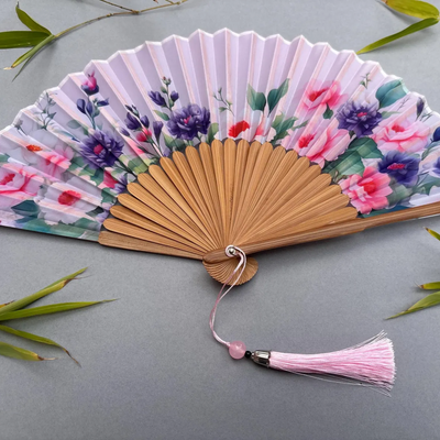 Handheld fan with floral design on a gray background