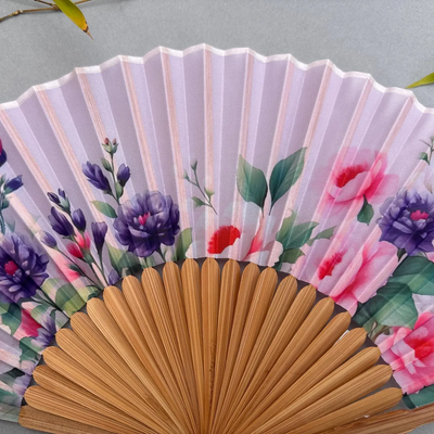 Handheld fan with floral design on a gray background