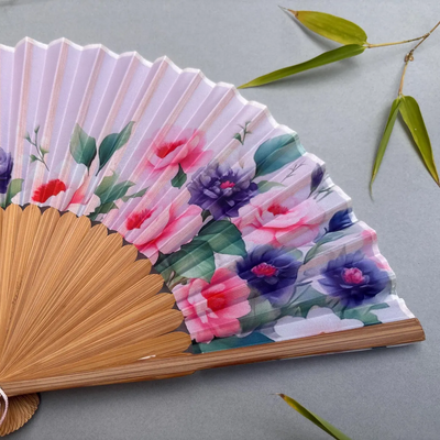 Handheld fan with floral design on a gray background