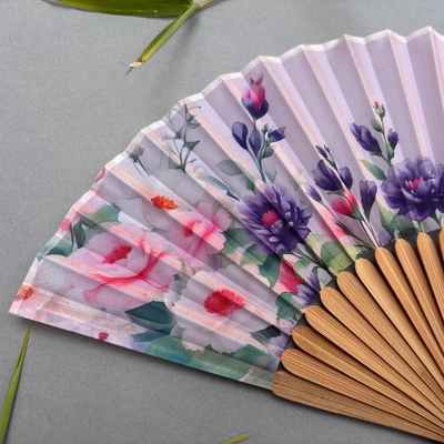 Handheld fan with floral design on a gray background