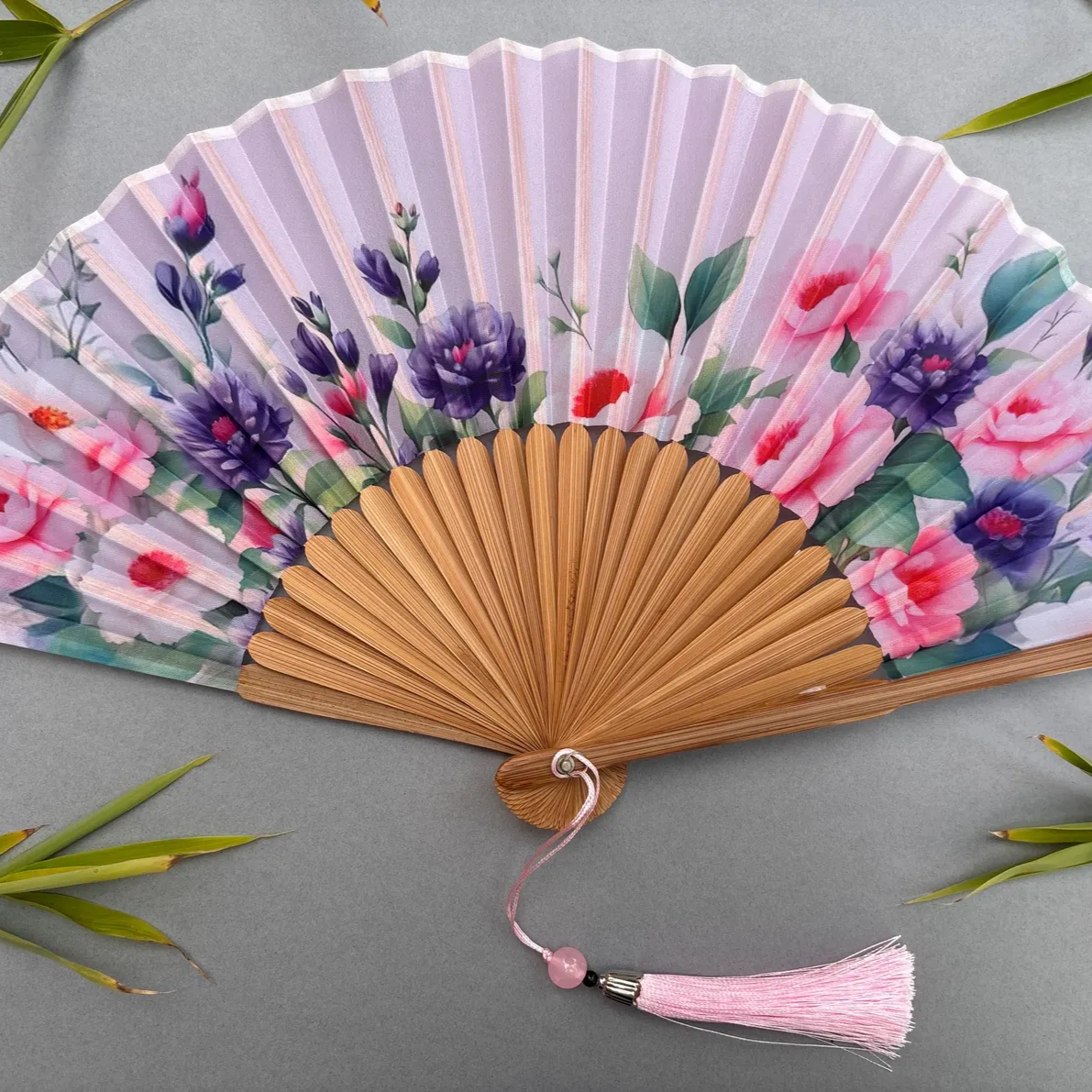 Handheld fan with floral design on a gray background