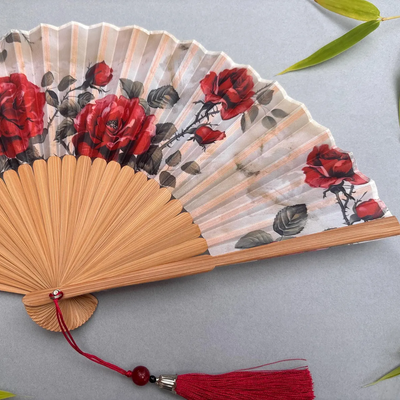 Handheld fan with red floral design on a gray background