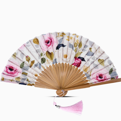 Floral patterned hand fan with wooden frame and pink tassel on a white background