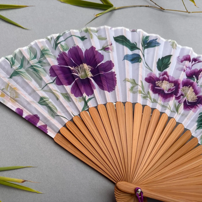 Floral-patterned hand fan with purple flowers on a gray background