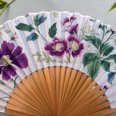 Floral-patterned hand fan with purple flowers on a gray background