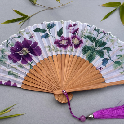 Floral-patterned hand fan with purple flowers on a gray background
