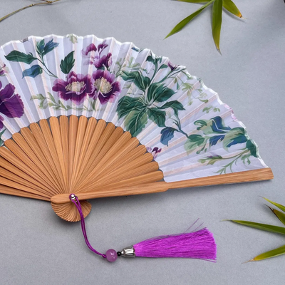 Floral-patterned hand fan with purple flowers on a gray background