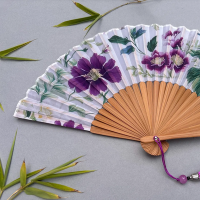 Floral-patterned hand fan with purple flowers on a gray background