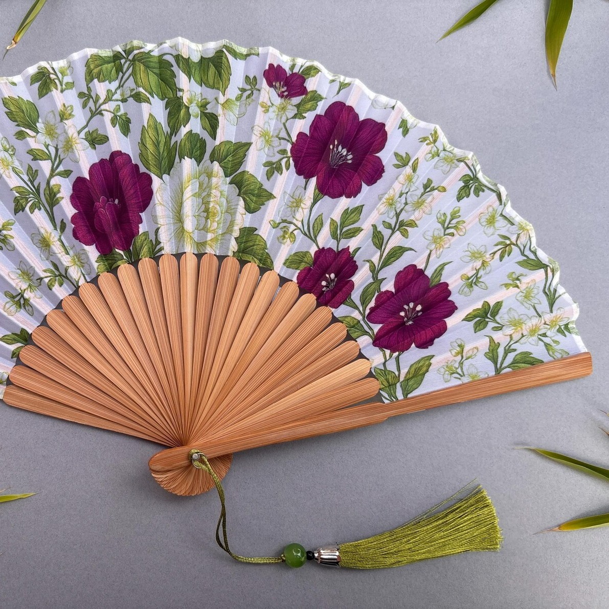 Floral-patterned hand fan on a gray background