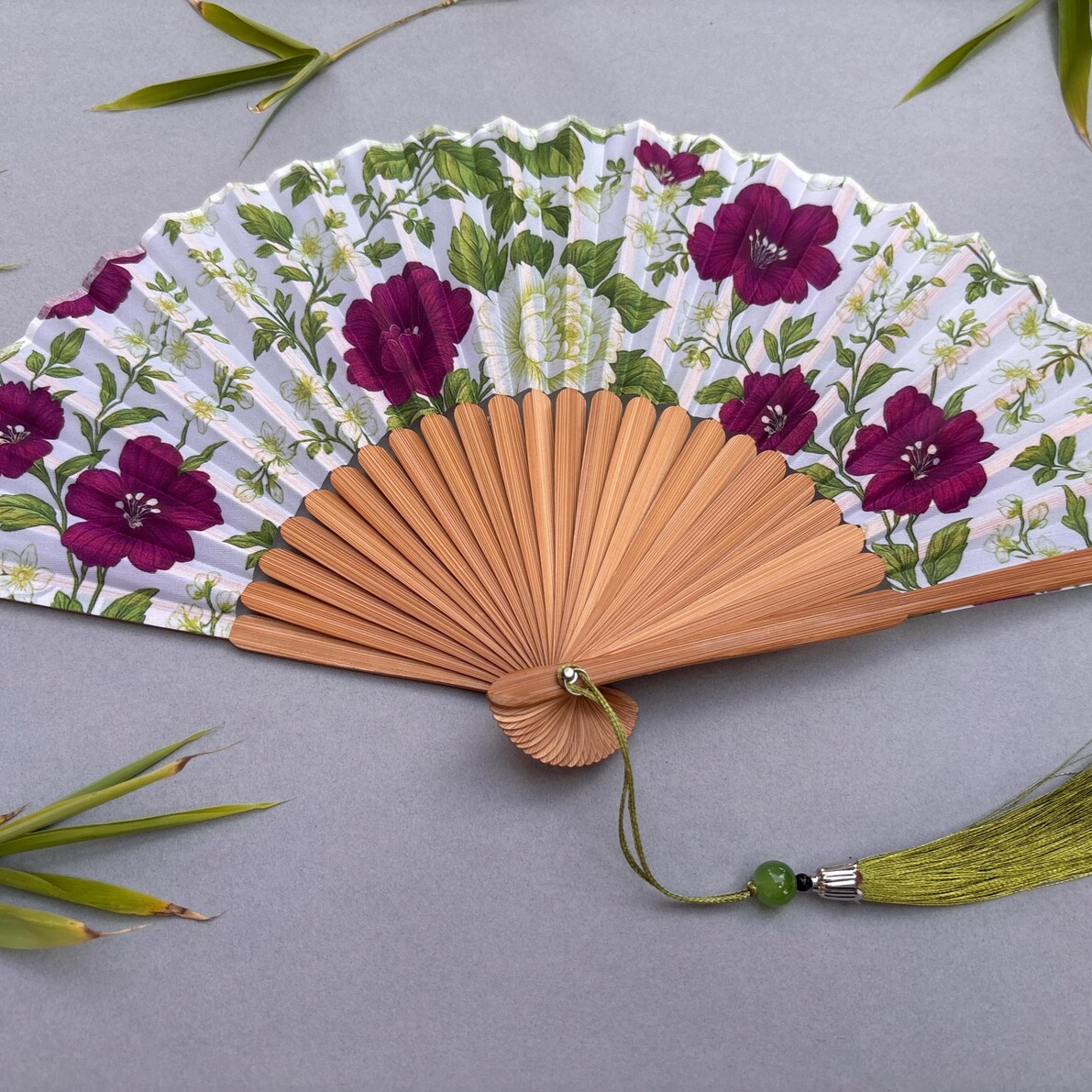 Floral-patterned hand fan on a gray background