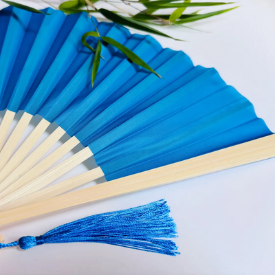 Baby Blue hand fan with a tassel on a light background