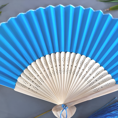 Blue and beige hand fan on a gray background
