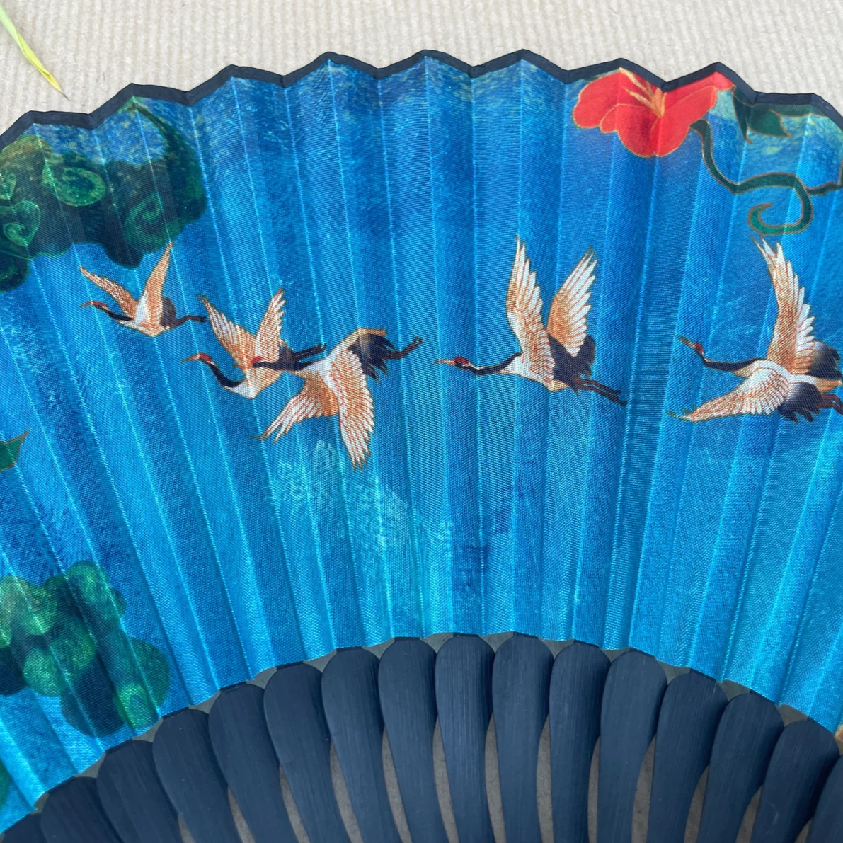 Handheld fan with blue background and bird illustrations