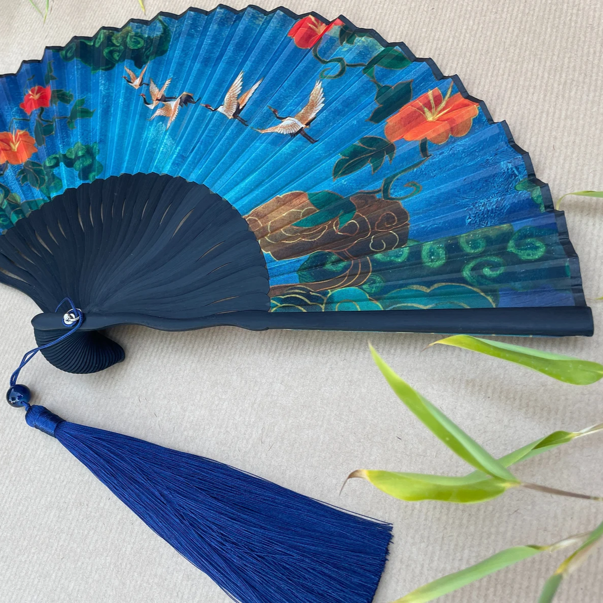 Decorative hand fan with blue tassel on a light background