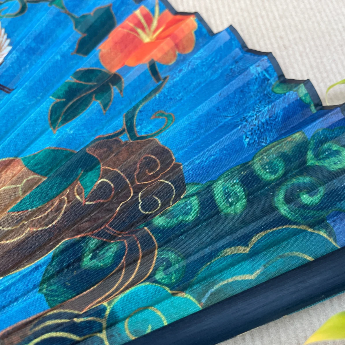 Handheld fan with blue background and bird illustrations