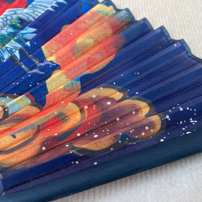 Colorful folded fan with abstract designs on a textured surface