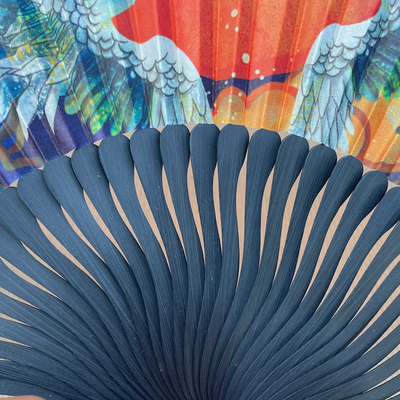 Close-up of a blue fan with colorful peacock feathers in the background